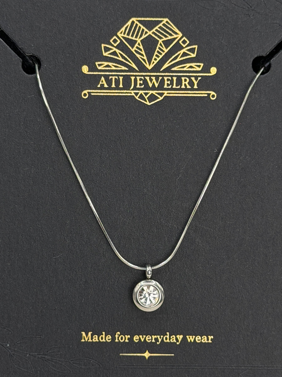 The Elara Necklace in polished stainless steel finish with clear crystal charm on ATI Jewelry card