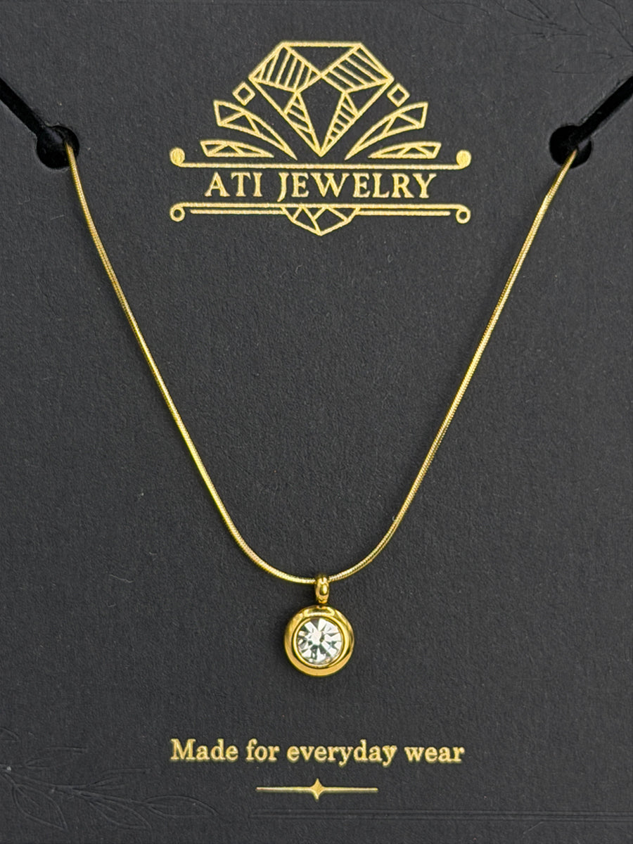 The Elara Necklace in 18K gold finish with clear crystal charm on ATI Jewelry card