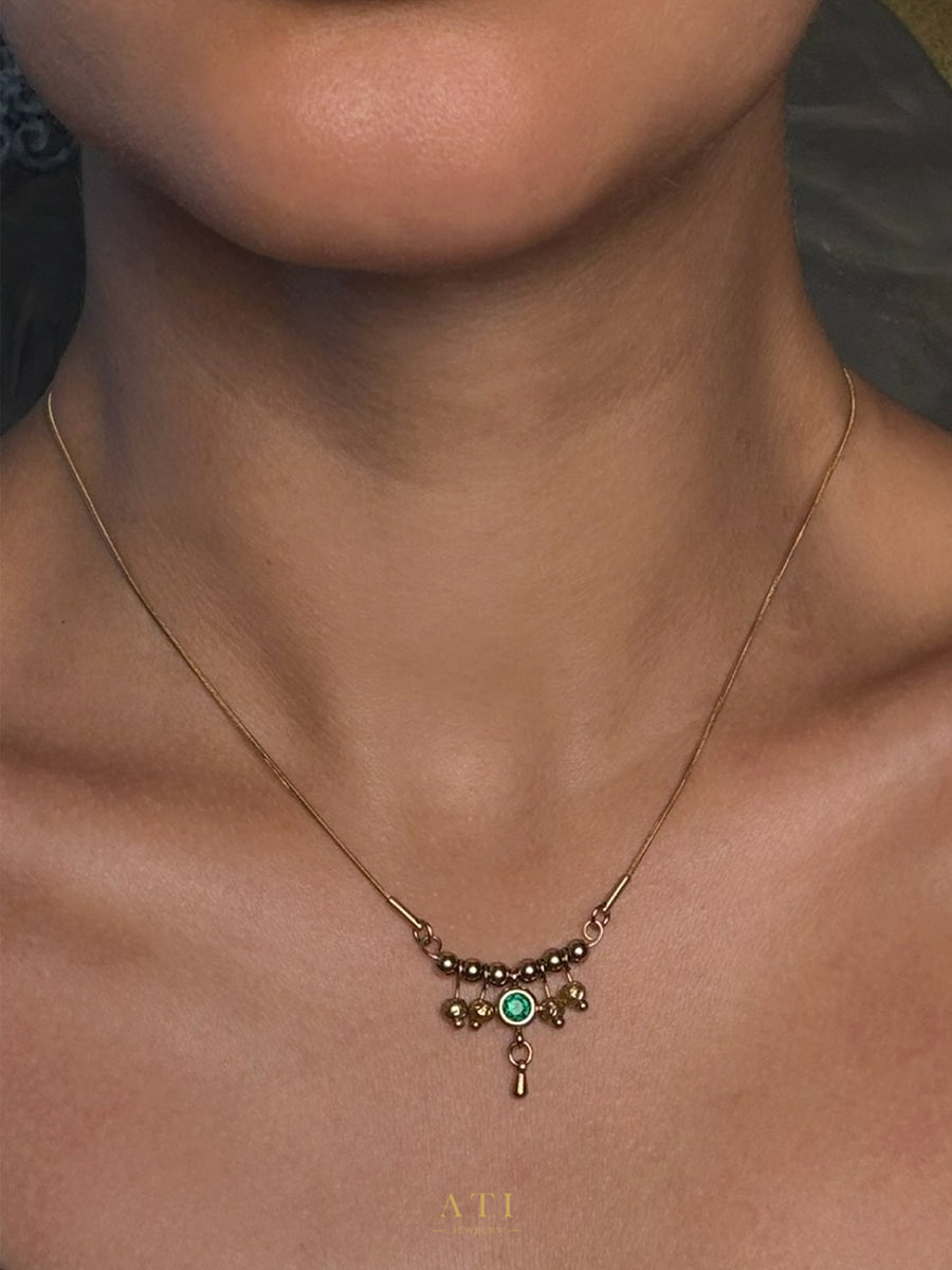 Close-up of Emerald Green crystal and gold details on The Queen Necklace