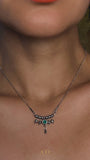 Close-up of Emerald Green crystal and polished stainless steel details on The Queen Necklace