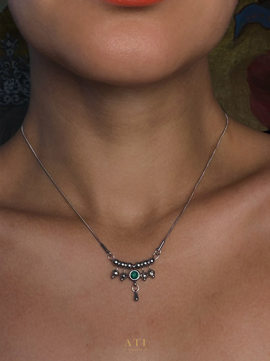 Close-up of Emerald Green crystal and polished stainless steel details on The Queen Necklace