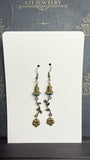 Antique brass-tone drop earrings with faceted teal beads, petal-shaped caps, curved leafy vines, and dangling flower charms.